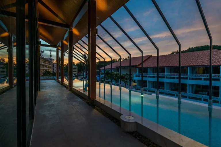 Covered walkway along the pool at Palmyrah Surin at dusk