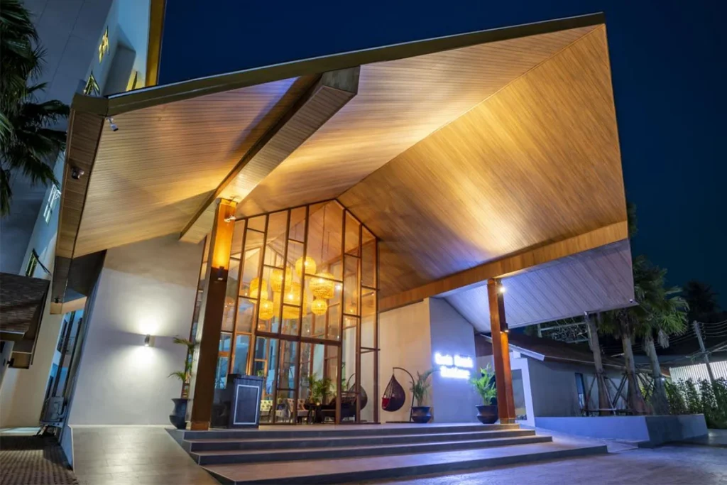 Entrance of Palmyrah Surin under a timber canopy at night