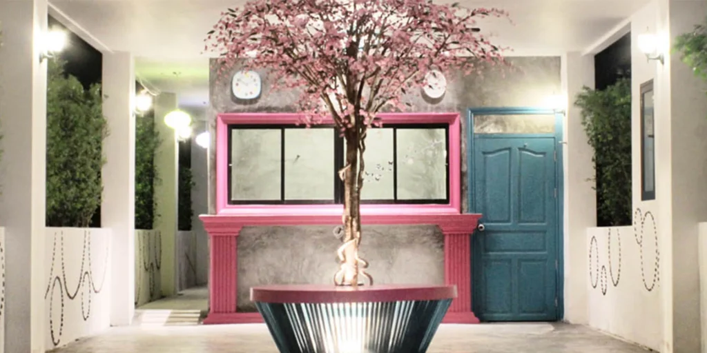 Lobby von Be My Guest mit einem blühenden Baum vor einem rosa Fensterrahmen