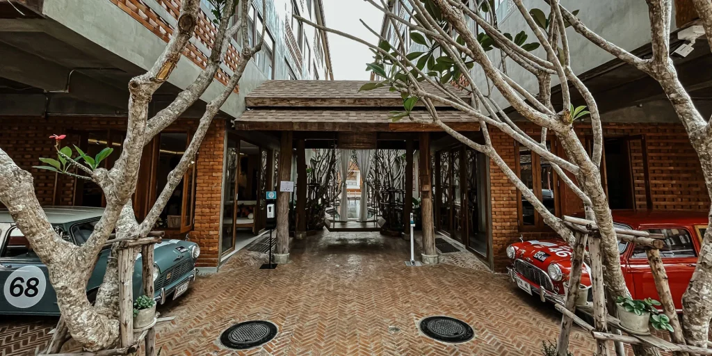 Entrance courtyard of Norn Nimman13 with frangipani trees and vintage cars